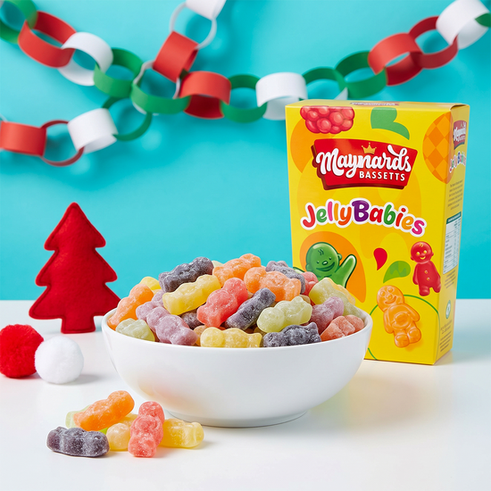 Box of Maynards Jelly Babies with a bowl of colorful candies, paper chains, and a small red Christmas tree.