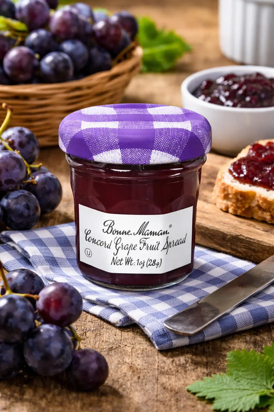 Jar of Bonne Maman Concord Grape Fruit Spread with grapes and a knife on a wooden surface