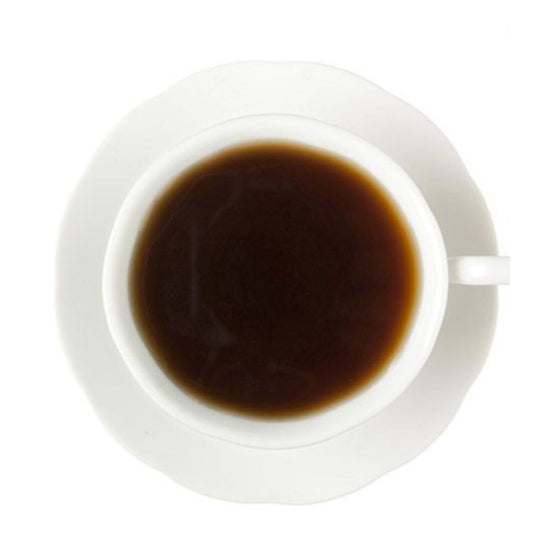 Dark hot black tea in a white teacup and on a white saucer all on a white background