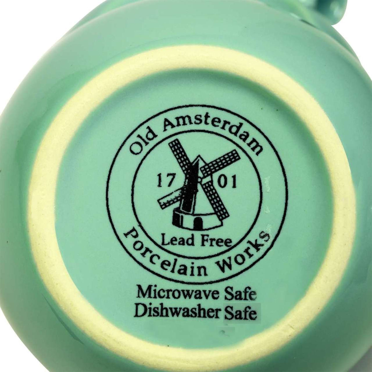 Close-up of the bottom of a sea foam green ceramic teapot with 'Old Amsterdam Porcelain Works' branding and safety information.