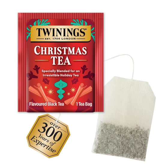 Red one tea bag package of Twinings Christmas Tea with a translucent tea bag with tea leaves and the tea label for over 300 years of expertise all on a white background.