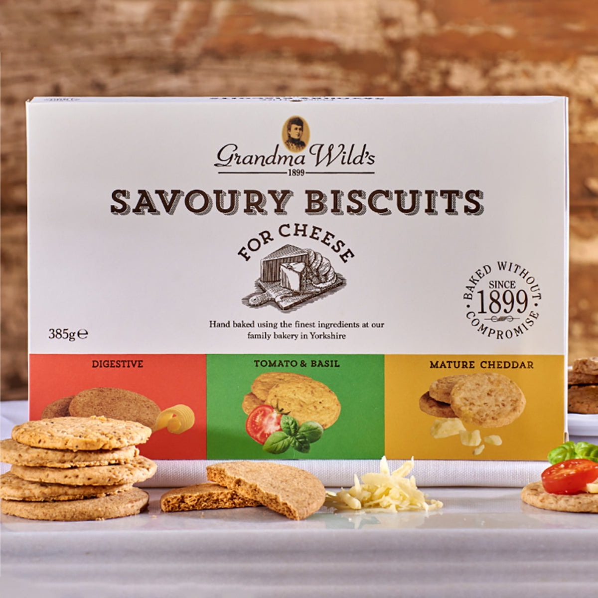 Box of Grandma Wild's Savoury Biscuits for Cheese with biscuits and ingredients on a wooden background