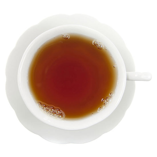 White cup and saucer with a dark amber raspberry black tea on a white background