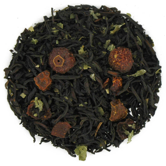 Tea ball with black tea leaves and dried fruits on a white background