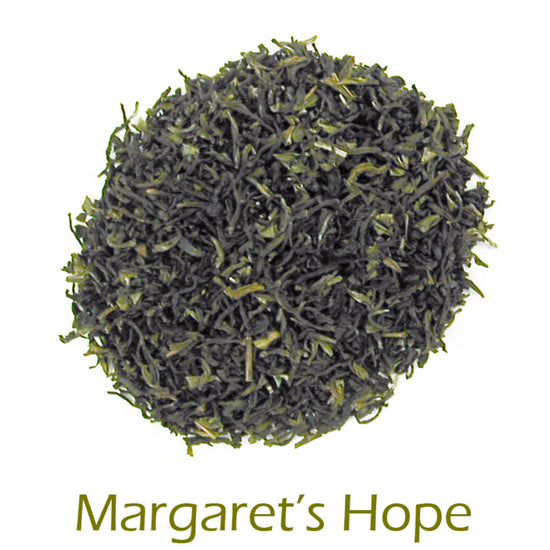 Close-up of green tea leaves with 'Margaret's Hope' branding on a white background