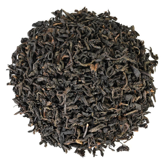 Pile of black dried tea leaves on a white background