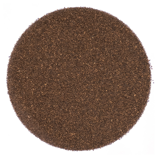Round pattern of dry dark brown tea leaves on a white background