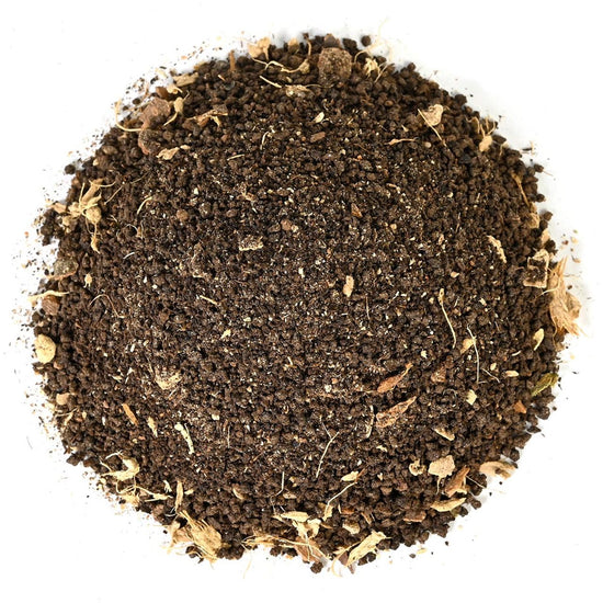 Close-up of dark brown grounded tea leaves on a white background
