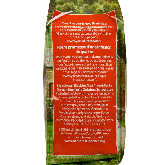 Side view of a bag of Yorkshire Tea with a pasture landscape behind a red block with white text displaying branding information and ingredients