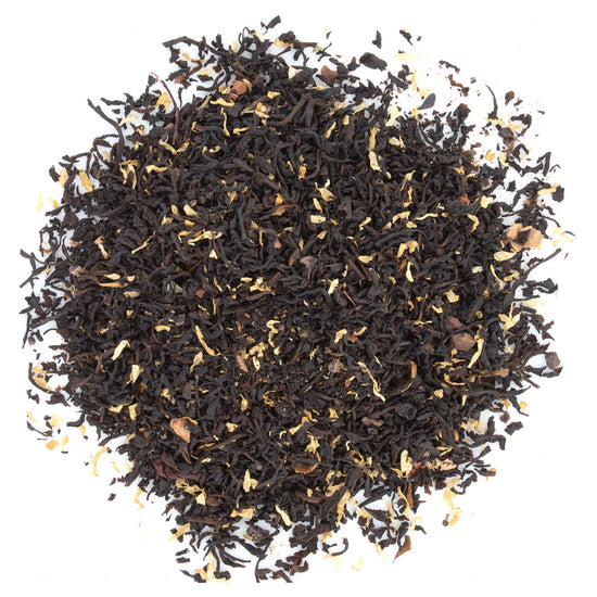 A close-up of flavored black tea loose leaf, showing the mix of black tea leaves, cocoa pieces, and camomile petals.