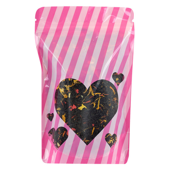 Tea bag packaging with pink and white striped design and heart-shaped black tea leaves on a white background