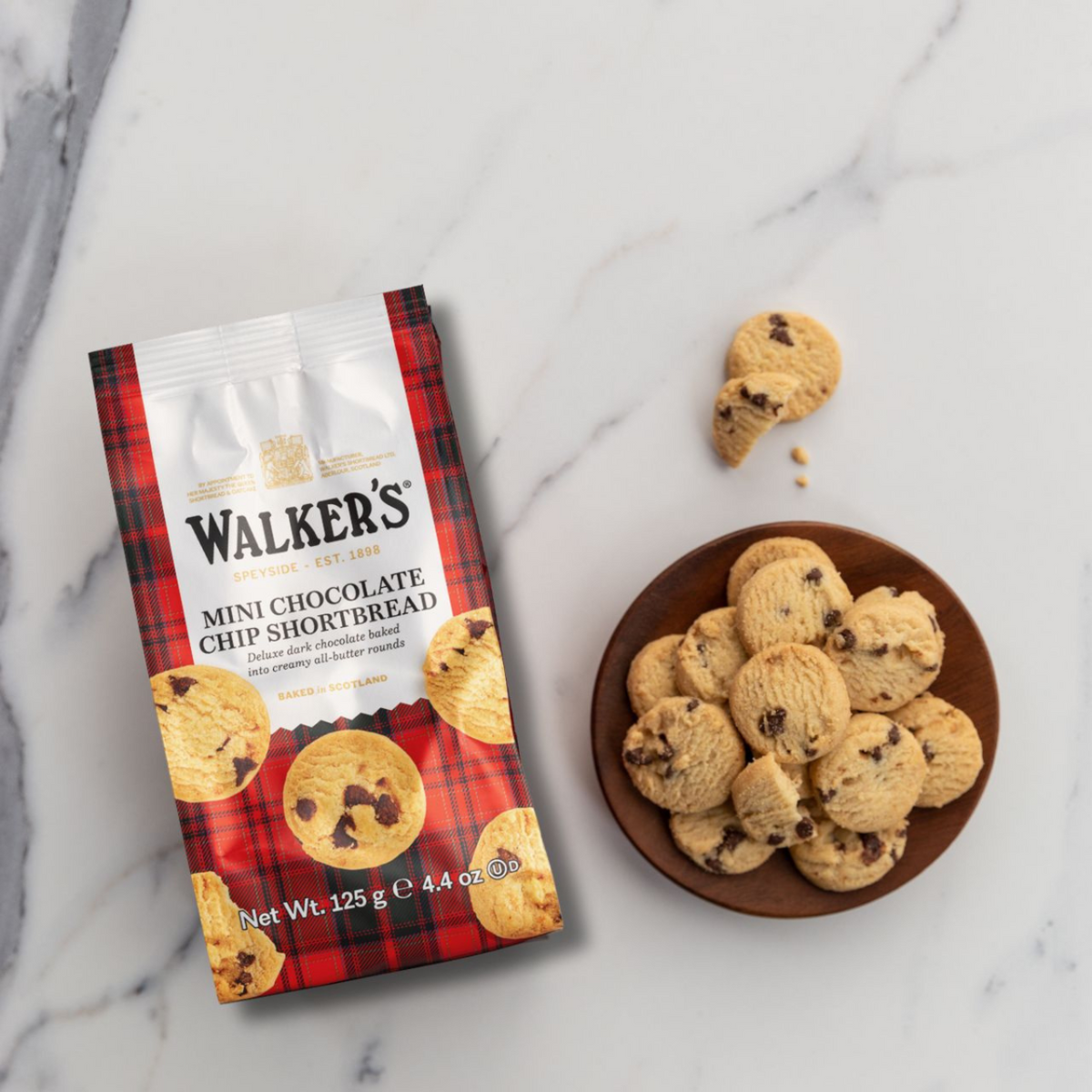 Walker's Mini Chocolate Chip Shortbread packaging on a marble surface with cookies.