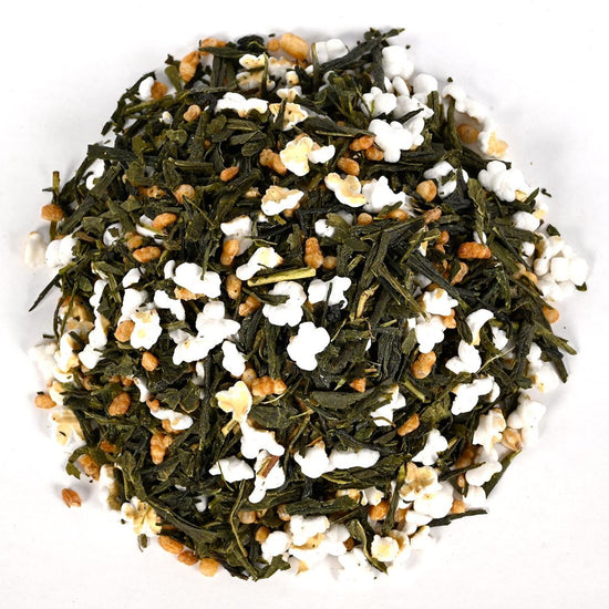 Mixture of green tea leaves, white flowers, and small orange elements on a white background