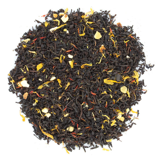 A close-up of loose leaf black tea with pieces of orange and cocoa visible among the leaves.