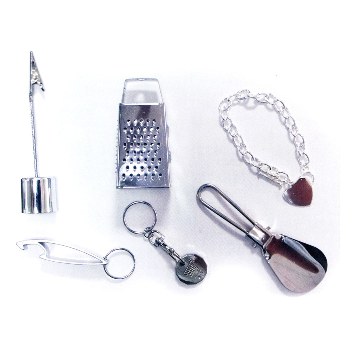 Contents of Christmas Cracker Poppers from Pudding Lane featuring a miniature cheese grater, key chains, and other trinkets.