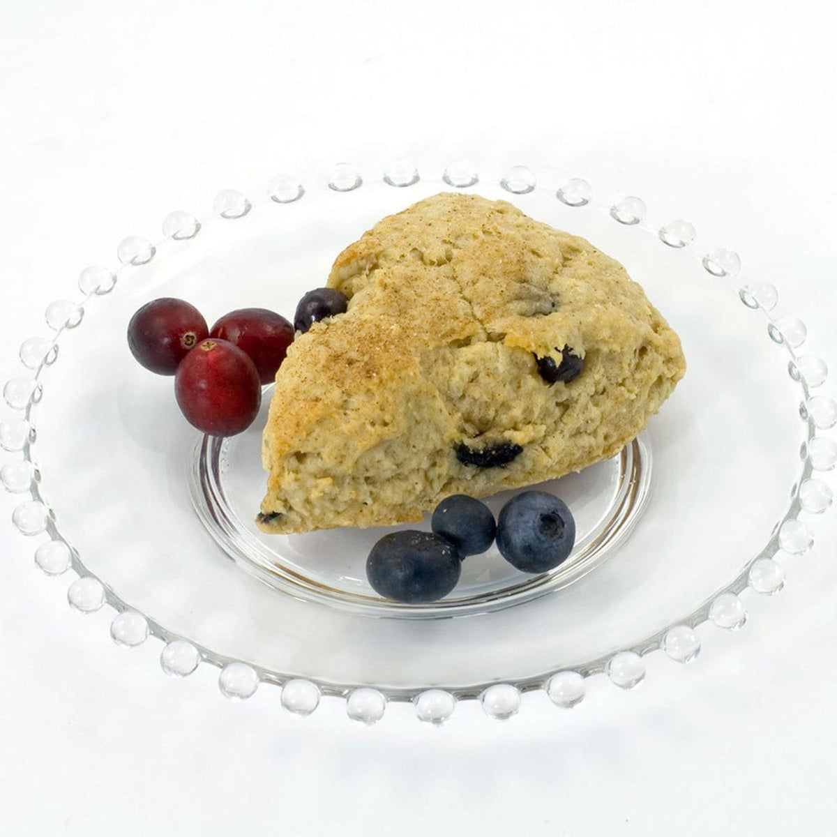 Baked oatmeal scone with berries on a clear glass plate with a white pearl rim