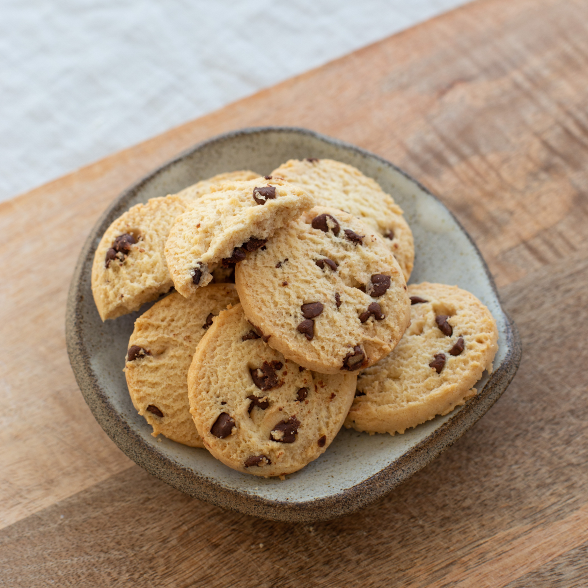A plate of Walker's Gluten Free Chocolate Chip Shortbread cookies on a wooden table.