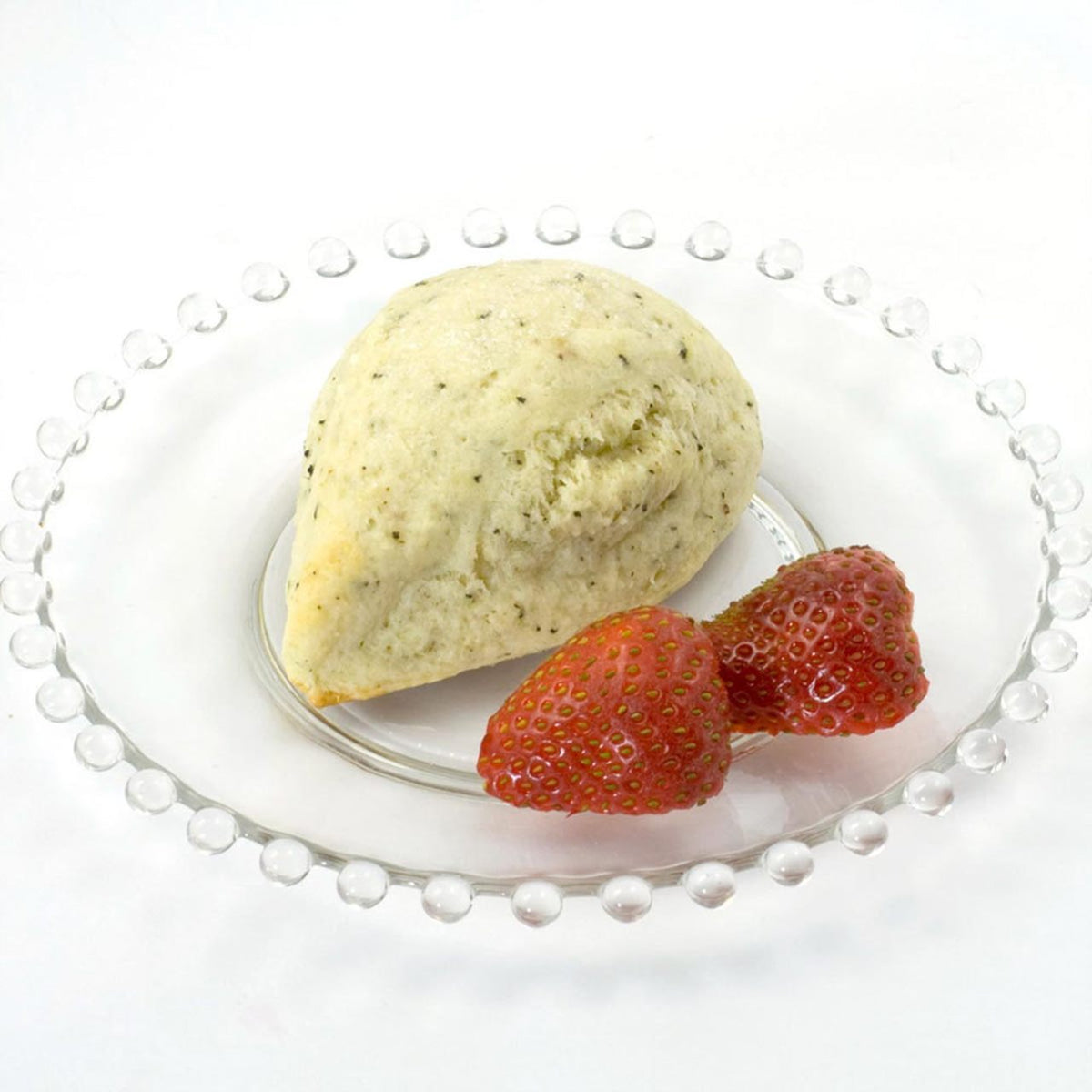 Indian Chai scone with two strawberries on a white plate with a pearl rim.