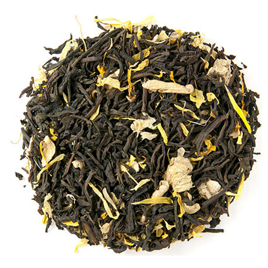 Tea ball with black tea leaves, ginger pieces, and yellow flowers on a white background