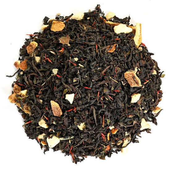 Loose-leaf black tea with visible spices and marigold colored petals on a white background