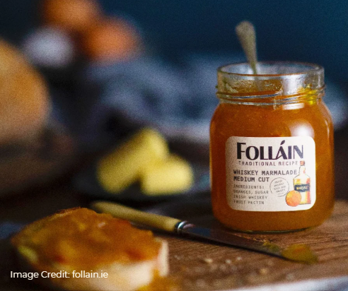 Jar of Folláin whiskey marmalade on a wooden surface with a blurred background