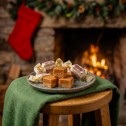 Plate of fudge on a stool draped with a green cloth in front of a fireplace with a stocking