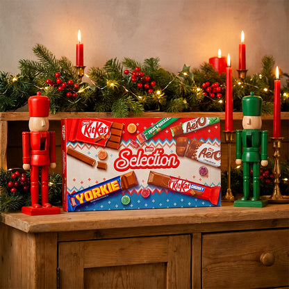 Nestlé Selection box on a wooden cabinet with nutcrackers, lit candles, and festive garland