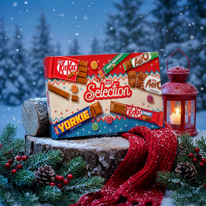 Nestlé Selection box on a snowy ledge with a red lantern, pine cones, and a red knitted scarf