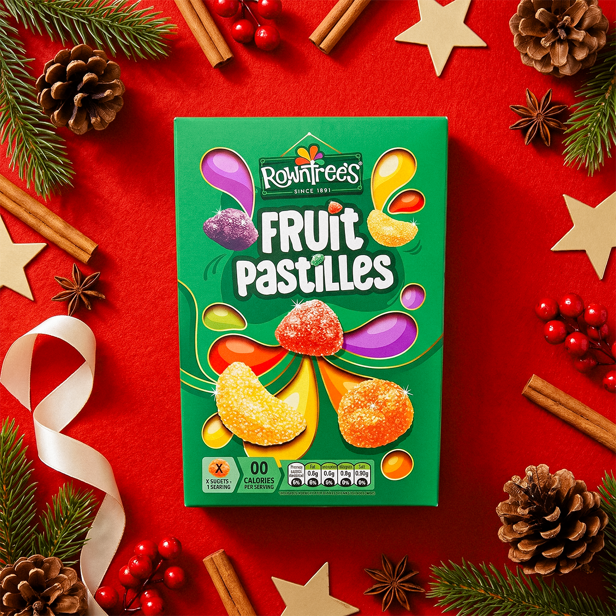 Rowntree’s Fruit Pastilles box on a red background with star anise, cinnamon sticks, and pine cones