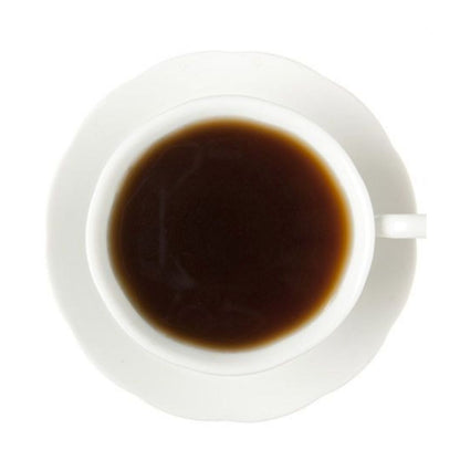 Dark hot black tea in a white teacup and on a white saucer all on a white background
