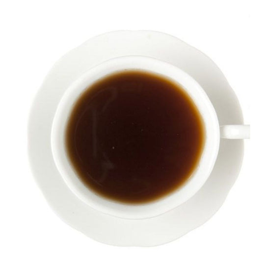 Top-down view of dark hot tea in a white cup and white saucer on a white background.