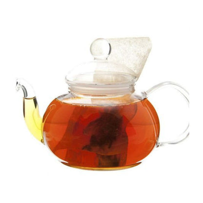 Glass teapot filled with hot amber tea and a teabag.