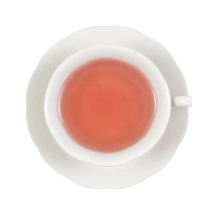 Pink colored hot tea in a white teacup on a white saucer, all on a white background.