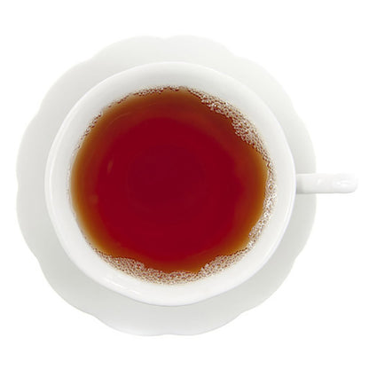 White cup filled with dark red hot tea on a white background