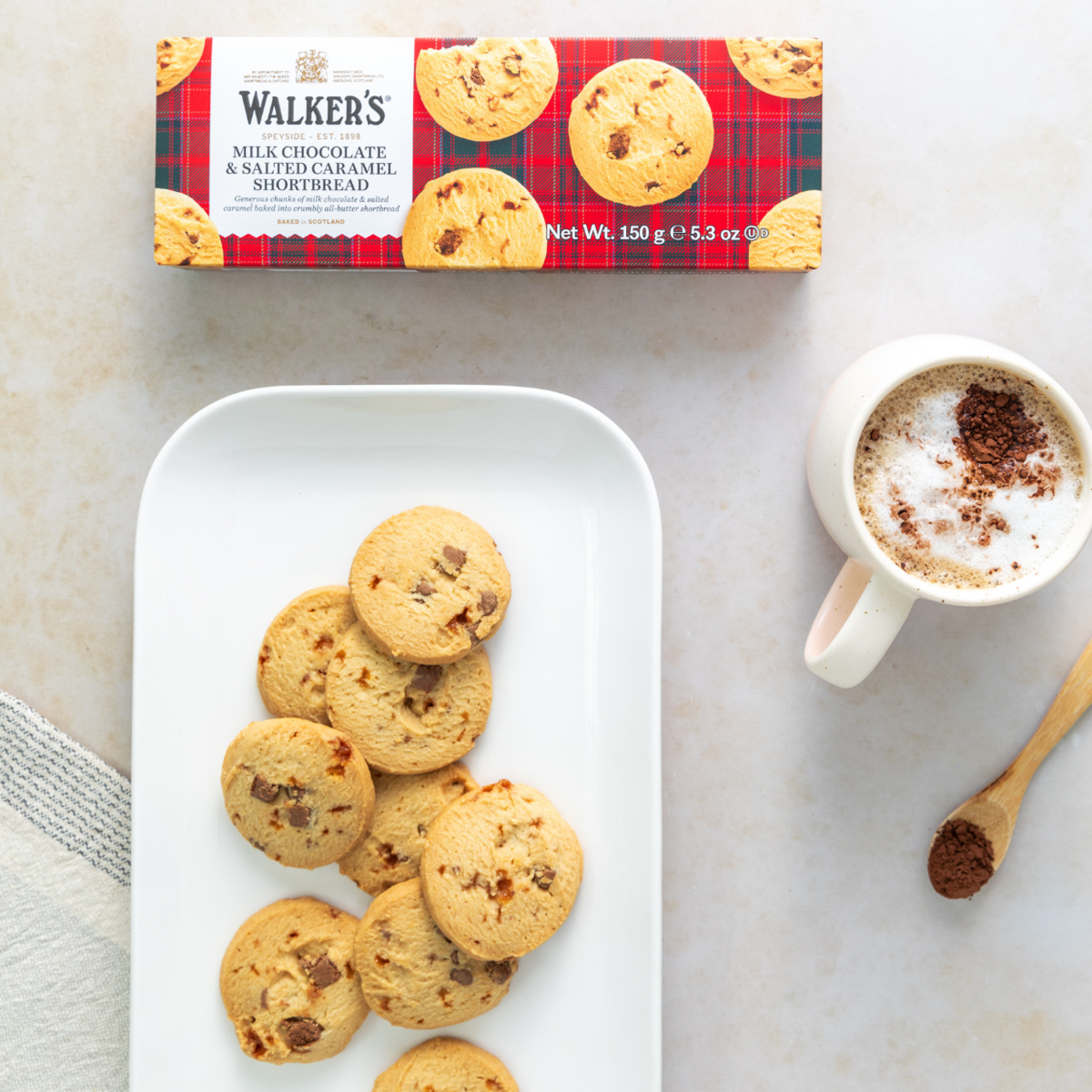 Walkers chocolate shortbread cookies on a plate with a mug of coffee and a box of cookies in the background.