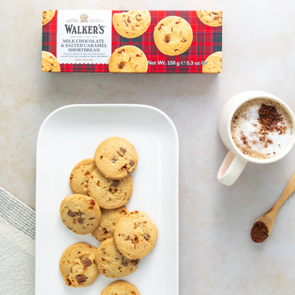 Walkers chocolate shortbread cookies on a plate with a mug of coffee and a box of cookies in the background.