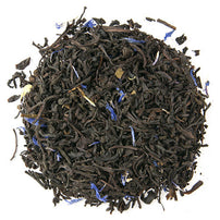 Close-up of Early Grey black tea leaves with blue flowers on a white background