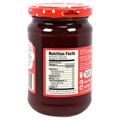 Jar of Abbey Farm Strawberry Preserve with a red lid on a white background.  Label shows nutrition information.