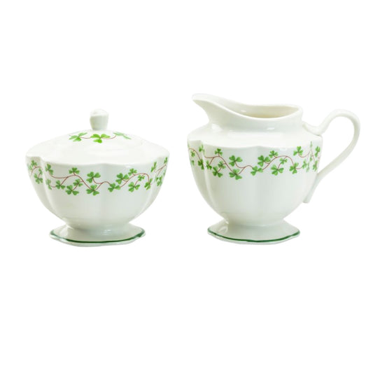 White sugar bowl and creamer set with green floral patterns on a white background