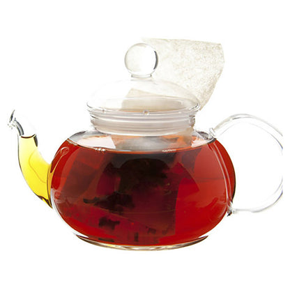Red colored tea in a glass teapot with a teabag inside on a white background