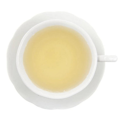 White teacup with a saucer containing a light yellow liquid tea on a white background