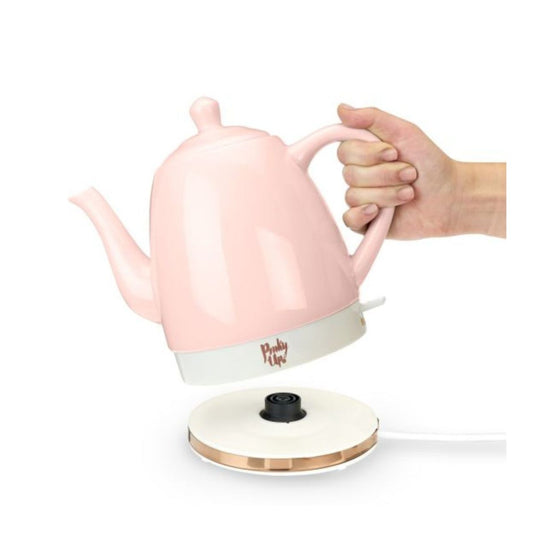 Pink electric kettle with a hand holding it on a white background