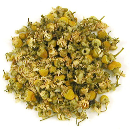 Heap of dried chamomile flowers and tea leaves on a white background