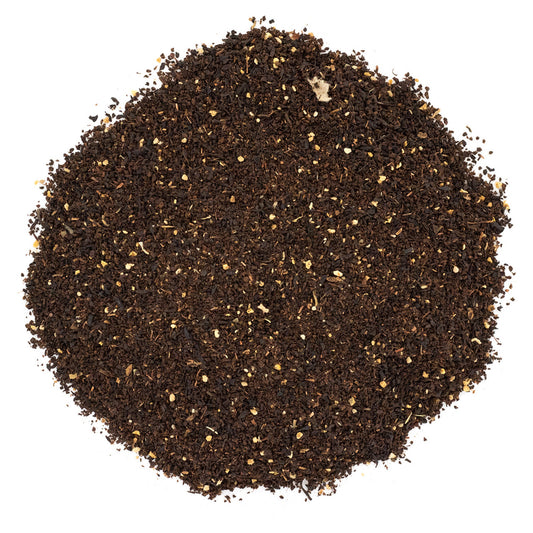 A pile of loose leaf black tea with pieces of peach and other herbs visible.
