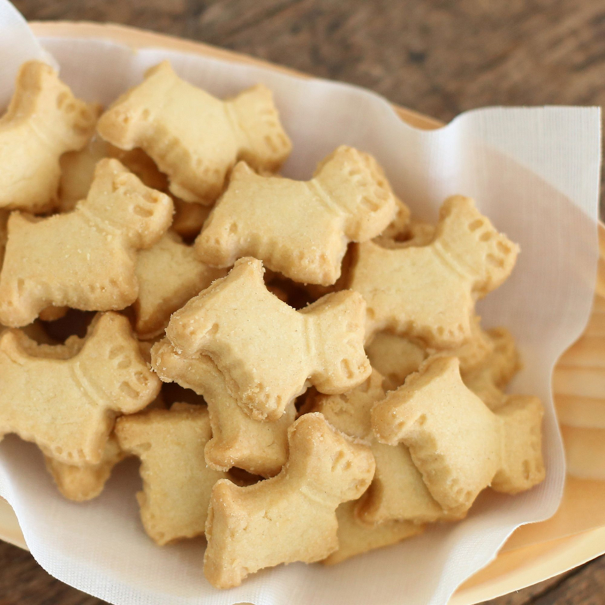 Dog bone-shaped cookies on a white plate with a wooden background