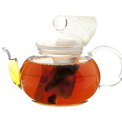 Clear glass teapot with a lid filled with tea on a white background