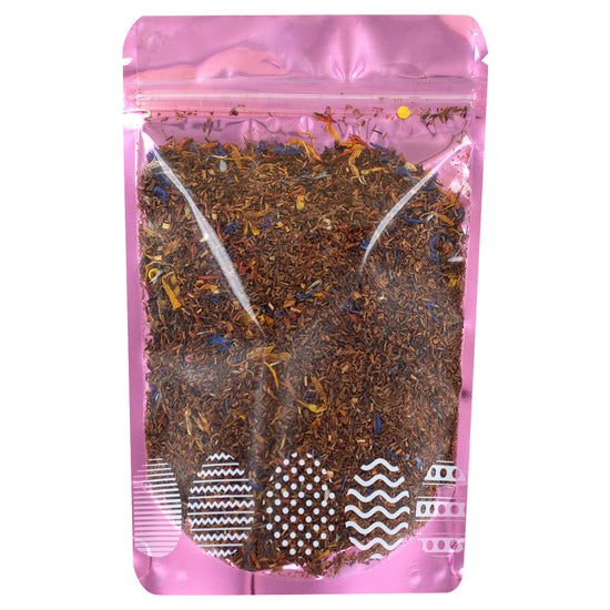 Pink packaging of a tea blend with visible leaves on a white background