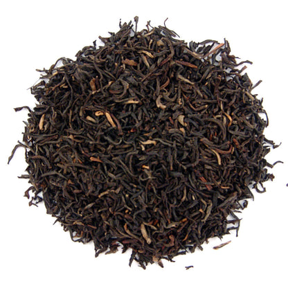 A pile of dry, black, tippy golden flowery orange pekoe loose leaf tea.