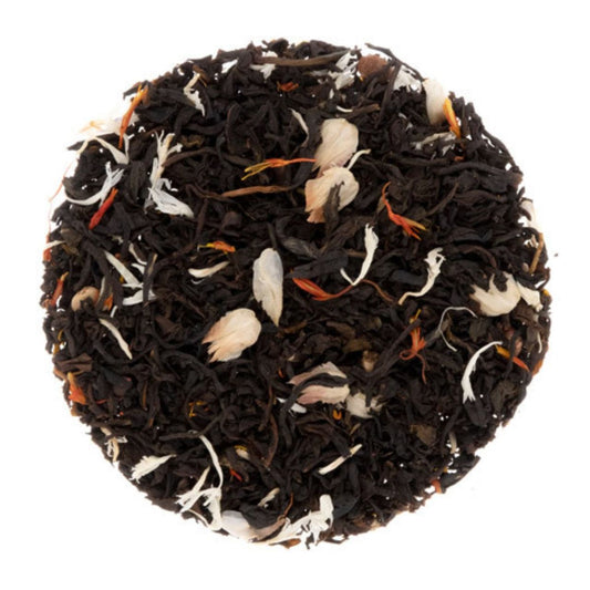 Black tea leaves with visible flowers and herbs on a white background