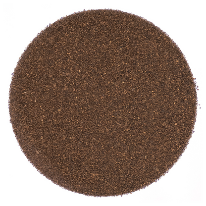 Round pattern of dry dark brown tea leaves on a white background